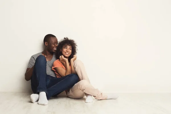 Casal afro-americano abraçando, sentado no chão — Fotografia de Stock