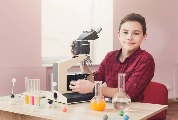 Schoolboy olhando em microscópio na lição — Fotografia de Stock