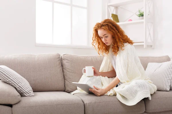 Mi godo il tempo libero a casa. Ragazza pensierosa con compressa e tazza di caffè — Foto Stock