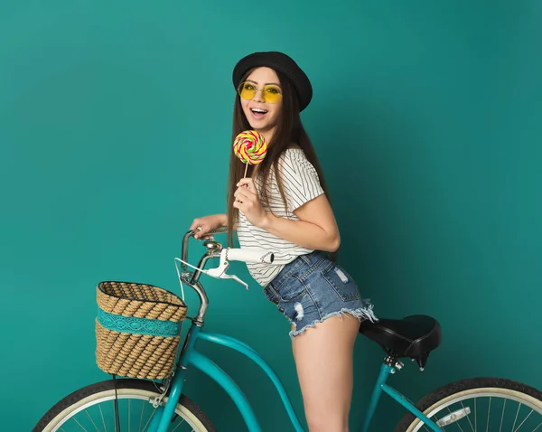 Happy girl posing with bicycle at blue studio background — Stock Photo, Image