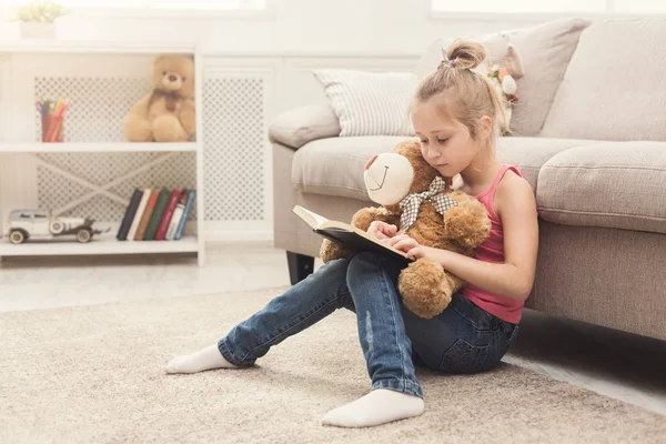 Lttle girl and her teddy bear reading book — Stock Photo, Image