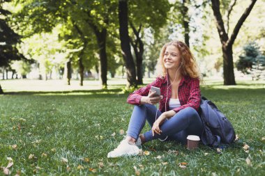 Oturma ve açık havada smartphone kullanarak güzel kadın