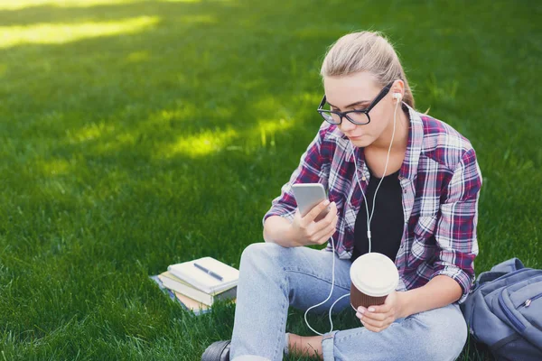 Mladá žena poslechu hudby na trávě venku — Stock fotografie
