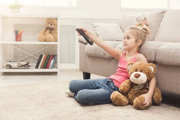 집에서 Tv를 캐주얼 아이가 바닥에 그녀의 장난감 베어와 스위칭 — 스톡 사진