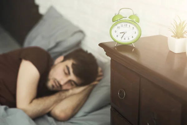 Hombre dormido y reloj en primer plano en el dormitorio — Foto de Stock