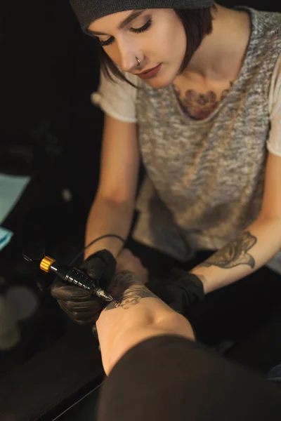 男性の腕に刺青をしている若い女性彫師 — ストック写真