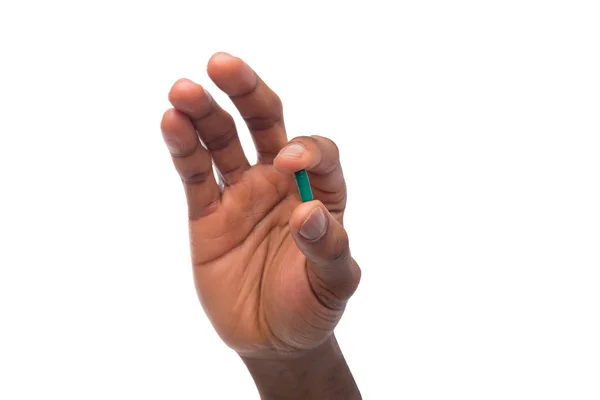 Mano negra sosteniendo una píldora aislada sobre fondo blanco — Foto de Stock