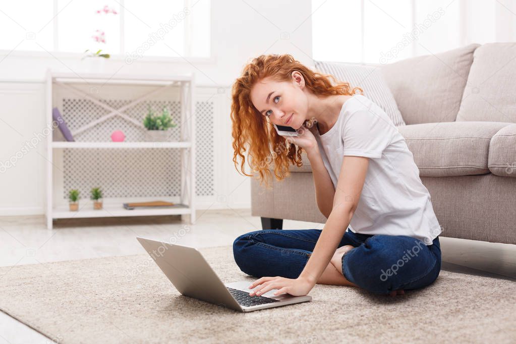 Girl using laptop and phone on the floor