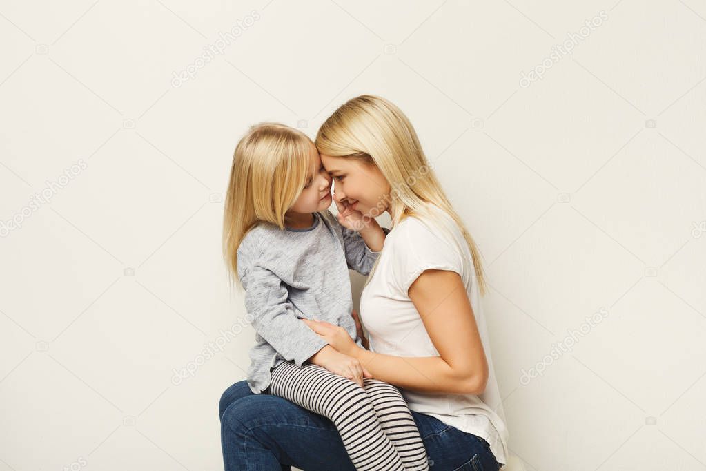 Happy mother and daughter embracing at white studio background