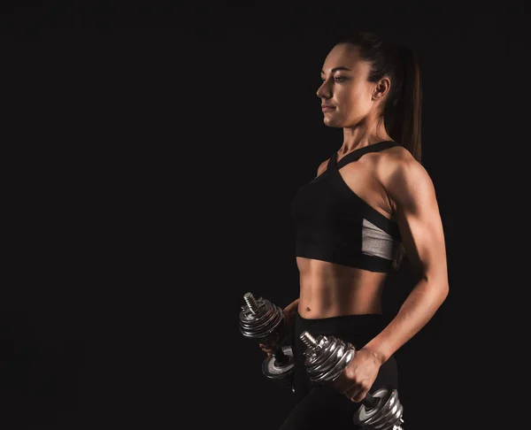 Bodybuilder femme avec haltères à fond noir — Photo