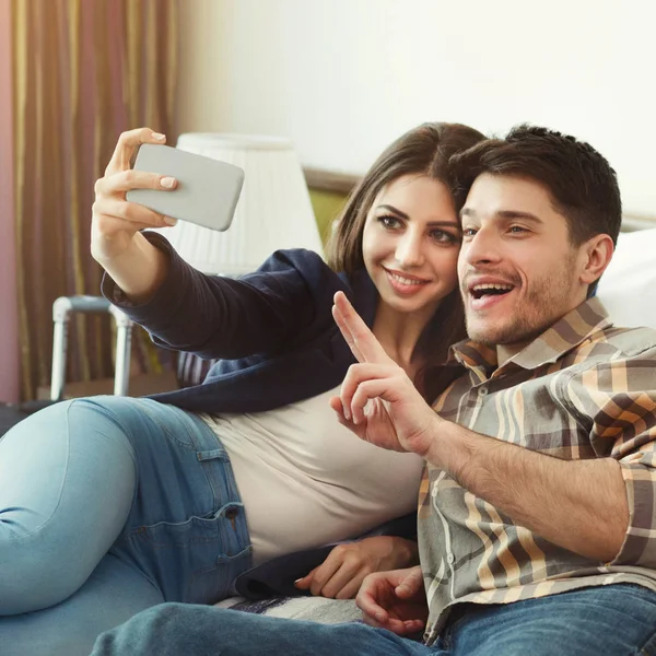 Šťastný pár odpočívá v hotelovém pokoji a s selfie — Stock fotografie