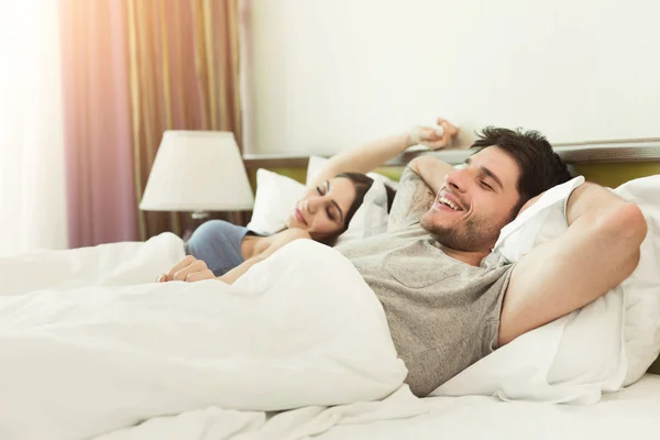 Feliz joven pareja despertando por la mañana en la cama —  Fotos de Stock