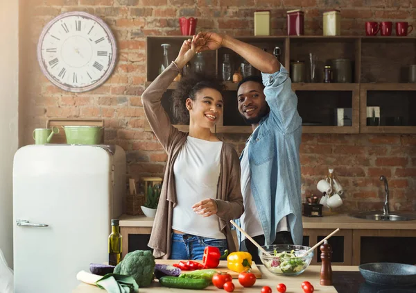 Africano americano pareja bailando cerca de mesa con comida en cocina — Foto de Stock