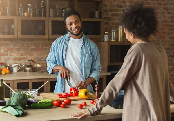 Africano americano hombre mirando esposa mientras cocinar ensalada — Foto de Stock