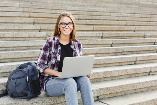 Estudiante sonriente sentado en escaleras usando laptop — Foto de Stock