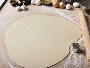 Mutfak masasının üstünde ince yuvarlak hamur rulo