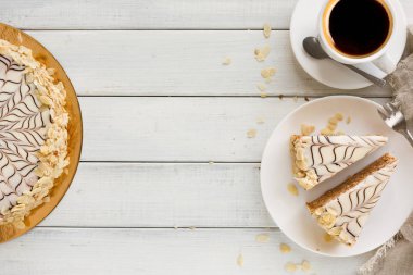 Kahve Kupası en iyi manzaralı beyaz tabakta Esterhazy pasta dilimlenmiş. Şarküteri şekerli tatlı badem beze hamur ve buttercream, geleneksel Macarca, Avusturya mutfağı ile.