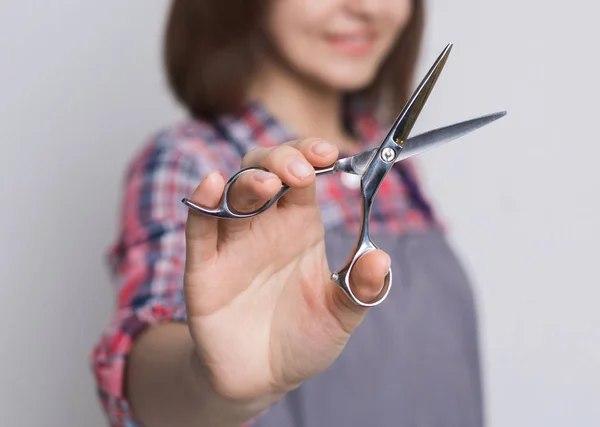 Fryzjer, trzymając nożyczki w studio szary tło — Zdjęcie stockowe