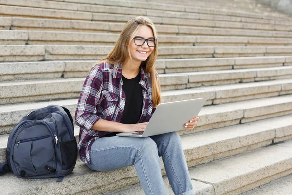 Lachende student zittend op trap met behulp van laptop — Stockfoto