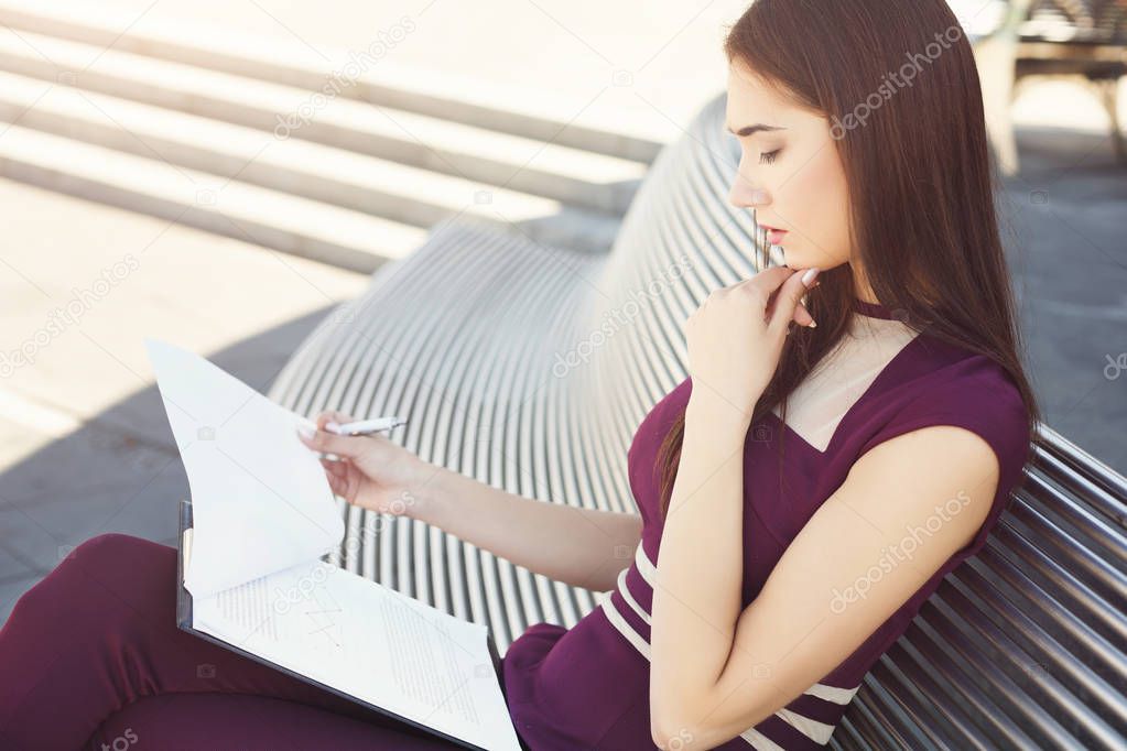 Caucasian businesswoman working with papers outdoors