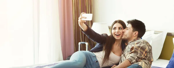 Casal amoroso descansando no quarto de hotel e tirando selfie — Fotografia de Stock