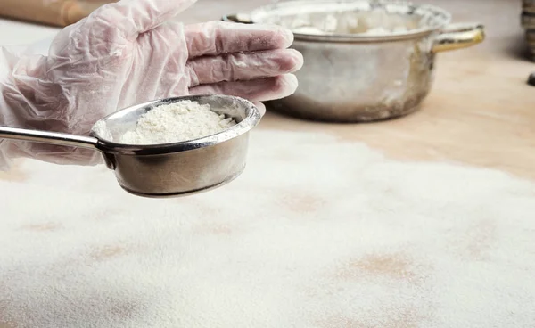 Male hands sifting flour from sieve on wooden kitchen table — Stock Photo, Image