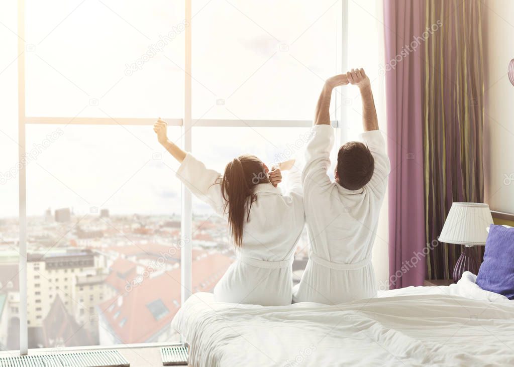 Young couple waking up in the morning in hotel room