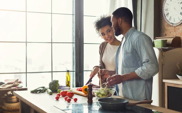 Loving afro american couple preparing dinner in kitchen