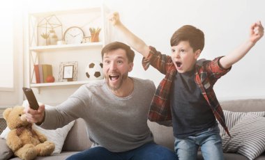 Baba ve oğul evde futbol TV izlerken.