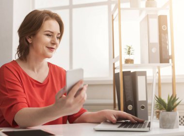 Dizüstü bilgisayarda yazarak ve akıllı telefon kullanma office iş kadını