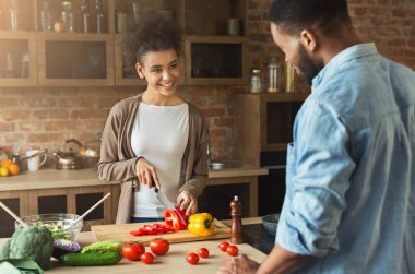 African american young woman looking at boyfriend while cooking salad clipart