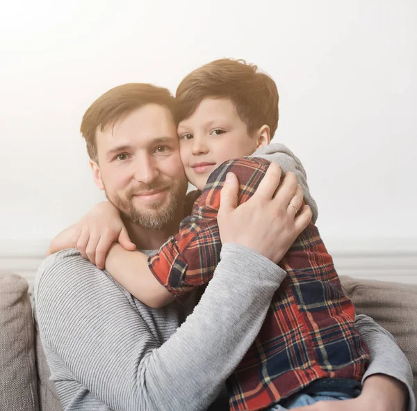 Тато і його син, обіймати на дивані в домашніх умовах — стокове фото
