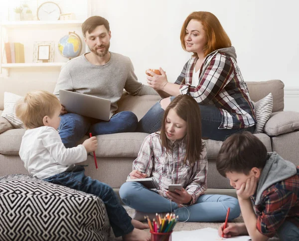 Children playing on the floor while parents on sofa — Stock Photo, Image