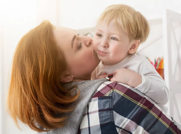 Young mother kissing son at home