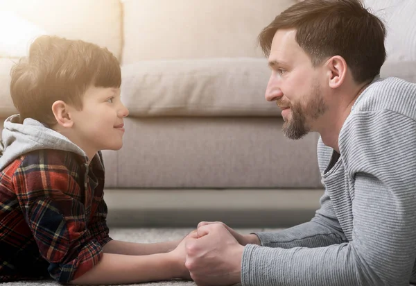 Vista lateral de padre e hijo guapos mirándose el uno al otro — Foto de Stock