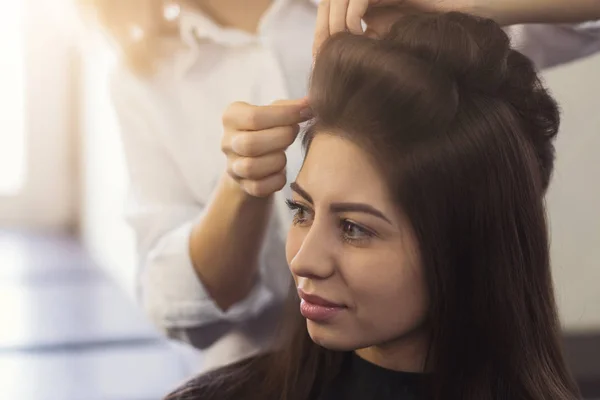 ヘアスタイリストは、茶色のクライアントの髪にカールを作る — ストック写真