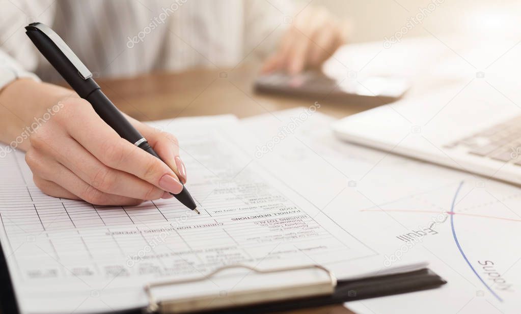 Female hand with pen and business report