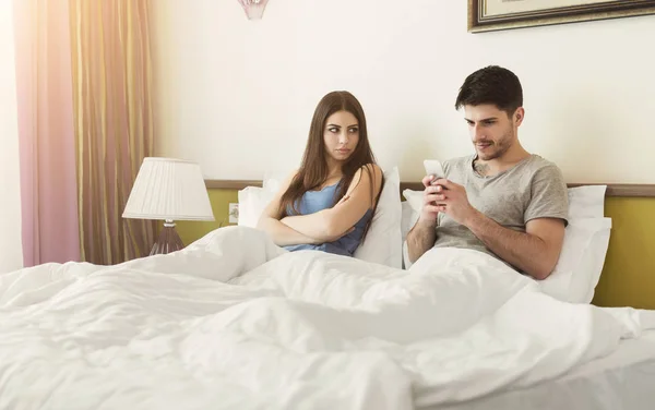 Mujer preocupada mirando al marido con adicción a los teléfonos inteligentes — Foto de Stock