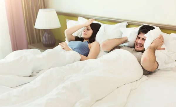 Jovem casal infeliz cobrindo ouvidos enquanto dormia na cama — Fotografia de Stock