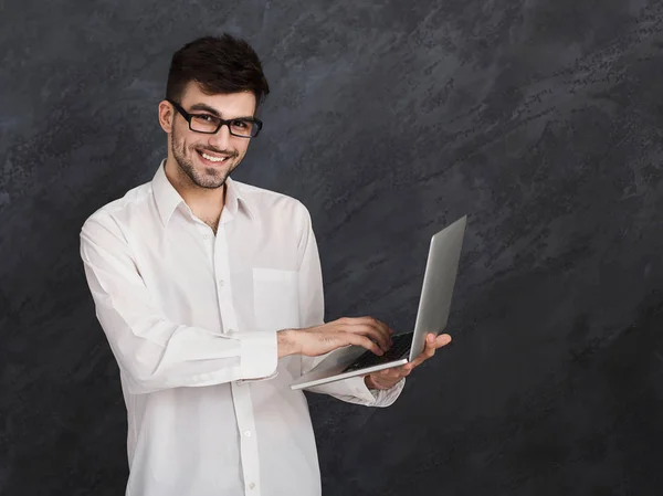 Smiling man using laptop at gray background — Stock Photo, Image