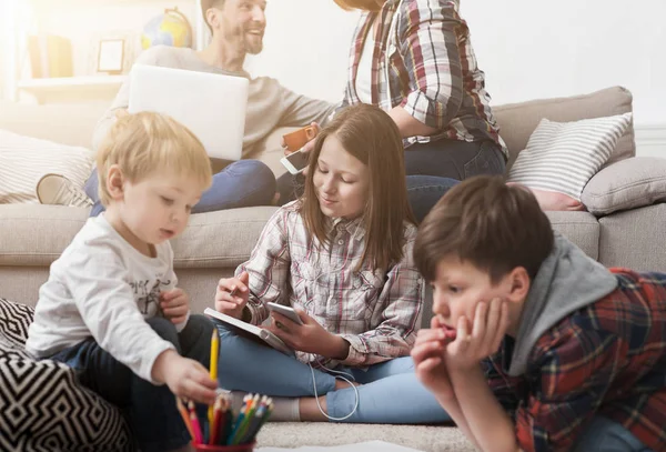 Kinder spielen auf dem Boden, während Eltern auf dem Sofa sitzen — Stockfoto