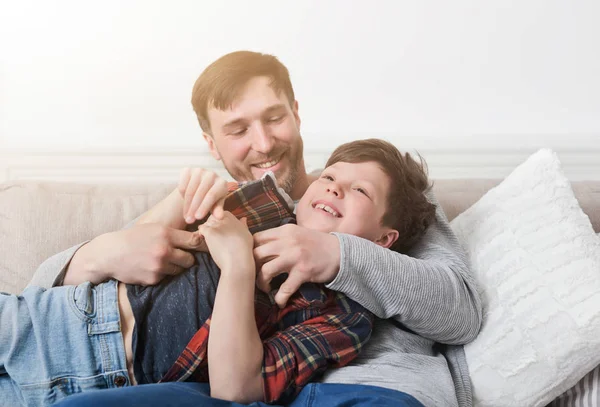 Любящий отец веселится со своим сыном на диване — стоковое фото