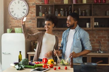 Happy black couple taking selfie with smartphone at kitchen clipart