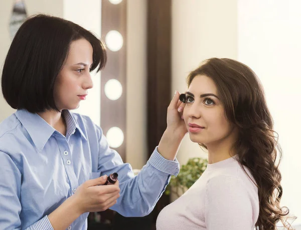 Visagist maakt wimpers voor mooi meisje — Stockfoto