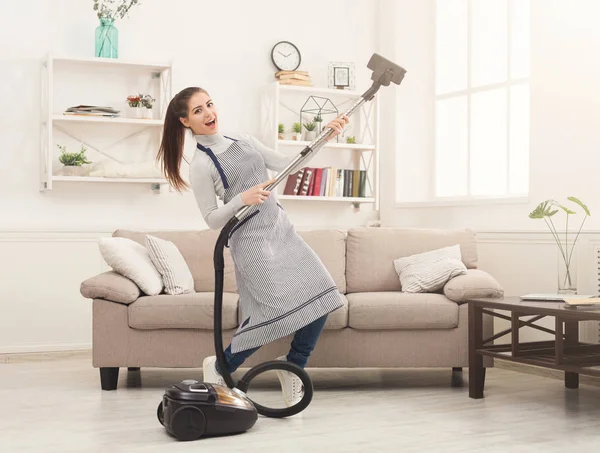 Щаслива жінка прибирає будинок з пилососом — стокове фото