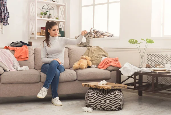 Desperate woman sitting on sofa in messy room — Stock Photo, Image