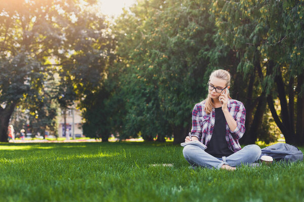 Young woman sitting with notebook on grass