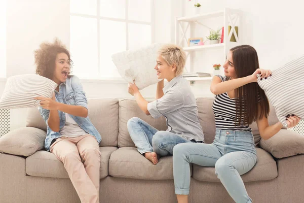 Три девушки дерутся подушками на диване — стоковое фото