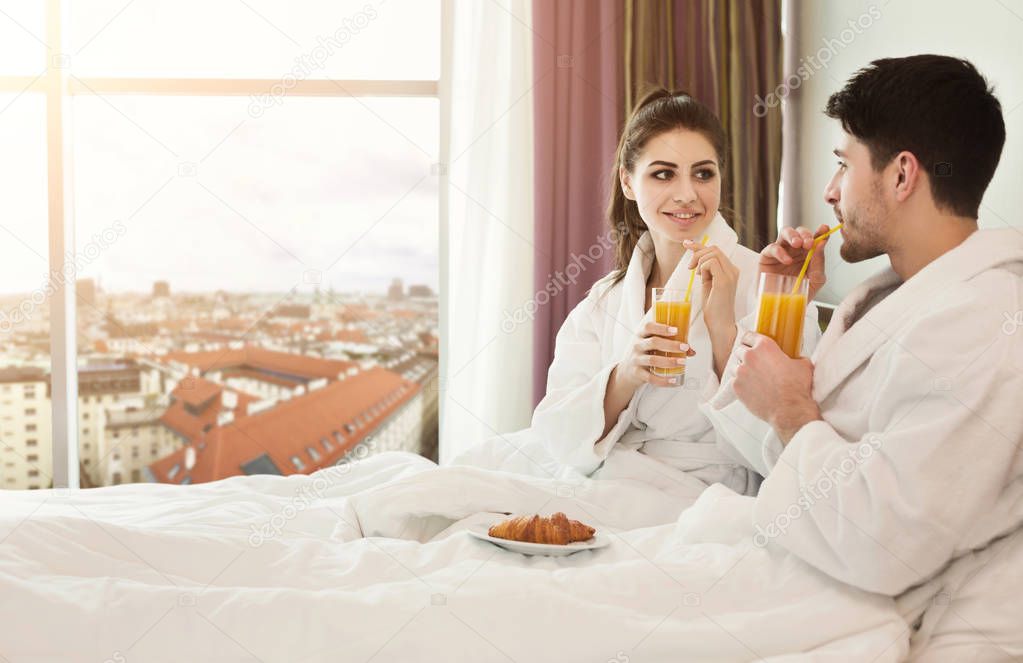Young happy couple having breakfast in bed