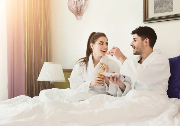 Verliefde paar liggend op bed en het ontbijt — Stockfoto